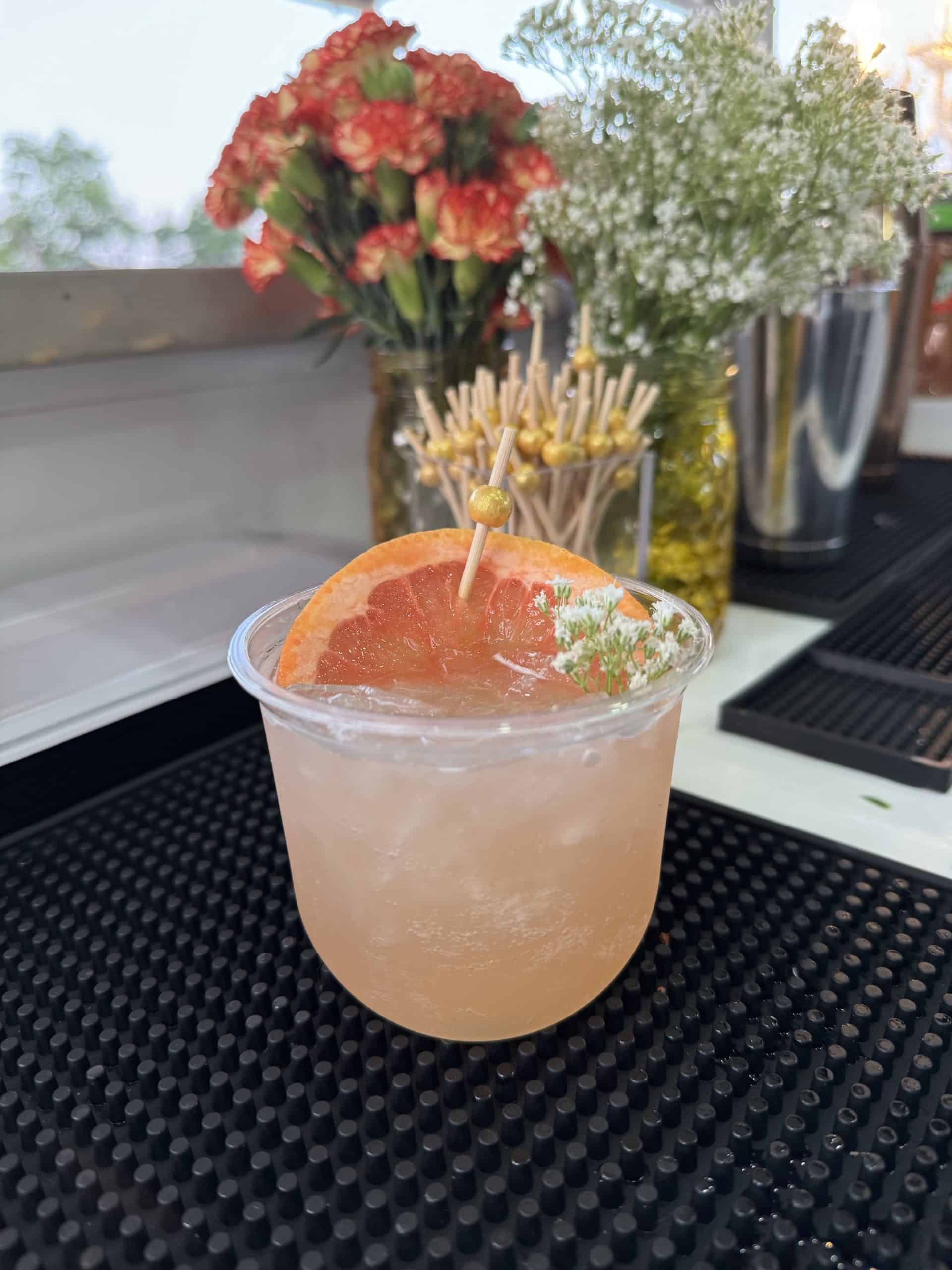 A pink cocktail garnished with grapefruit and baby's breath