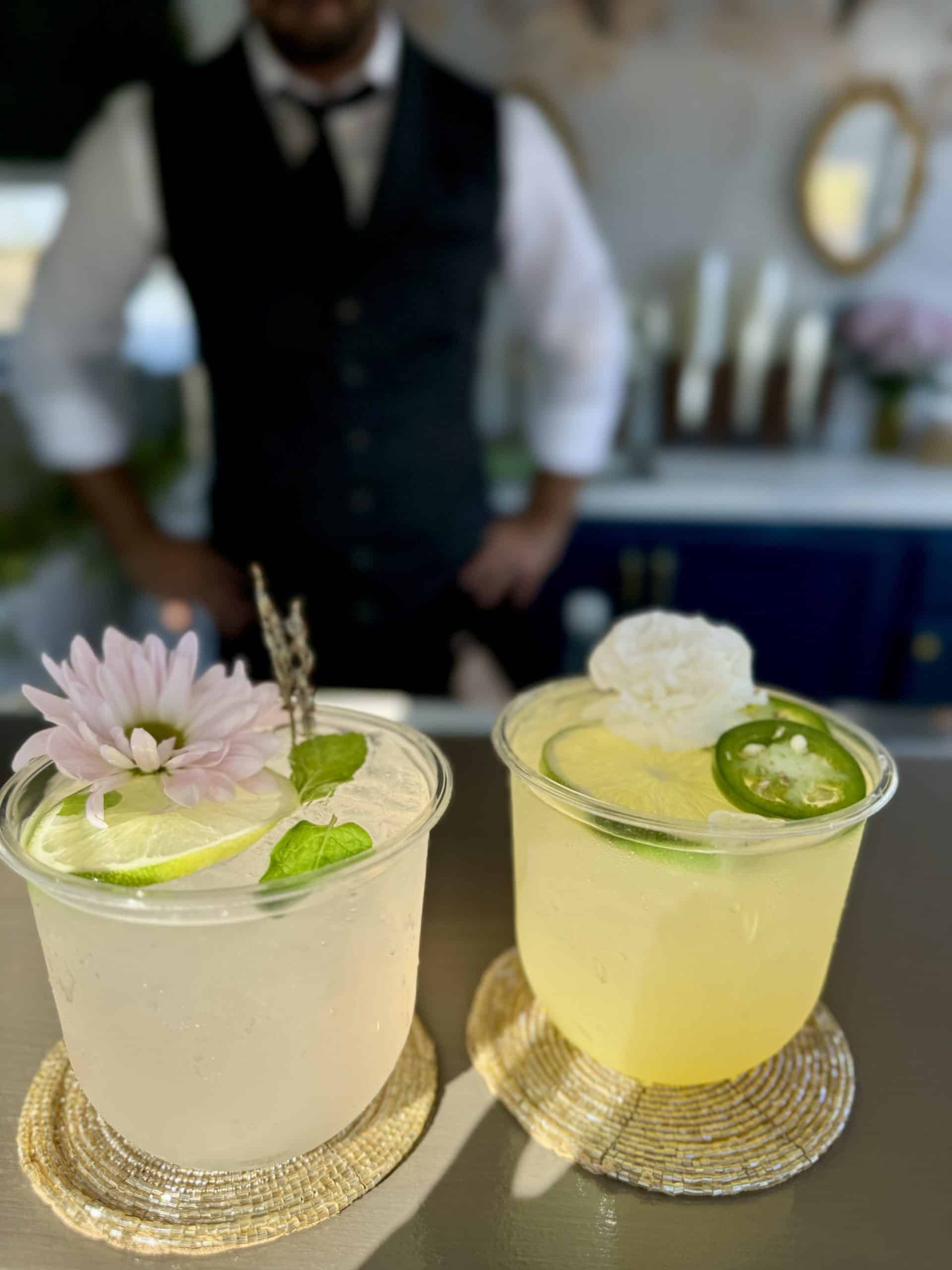 Two signature cocktails styled with floral and jalapeño garnishes