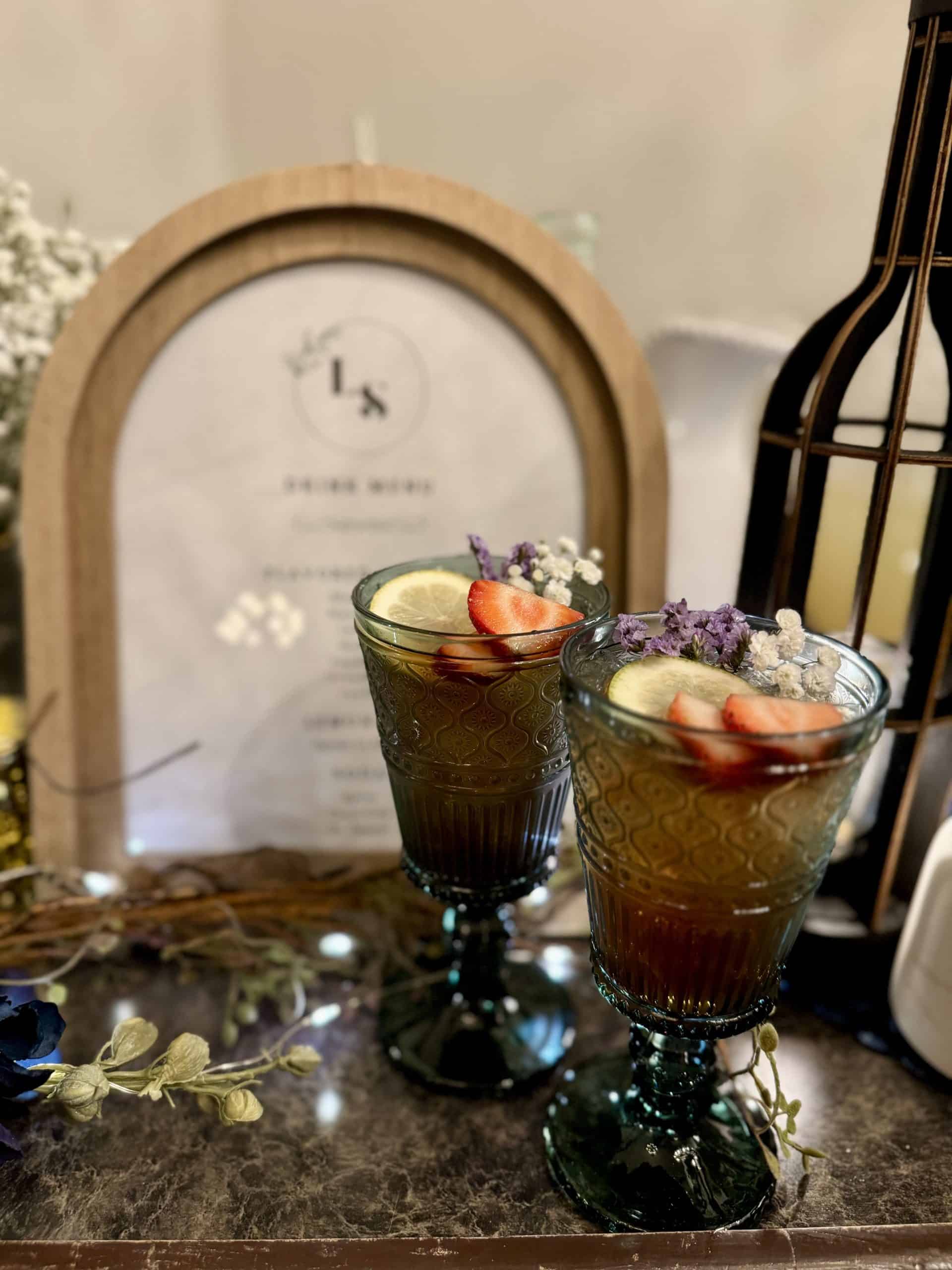 Two amber signature cocktails garnished with strawberry, lemon, and lavender
